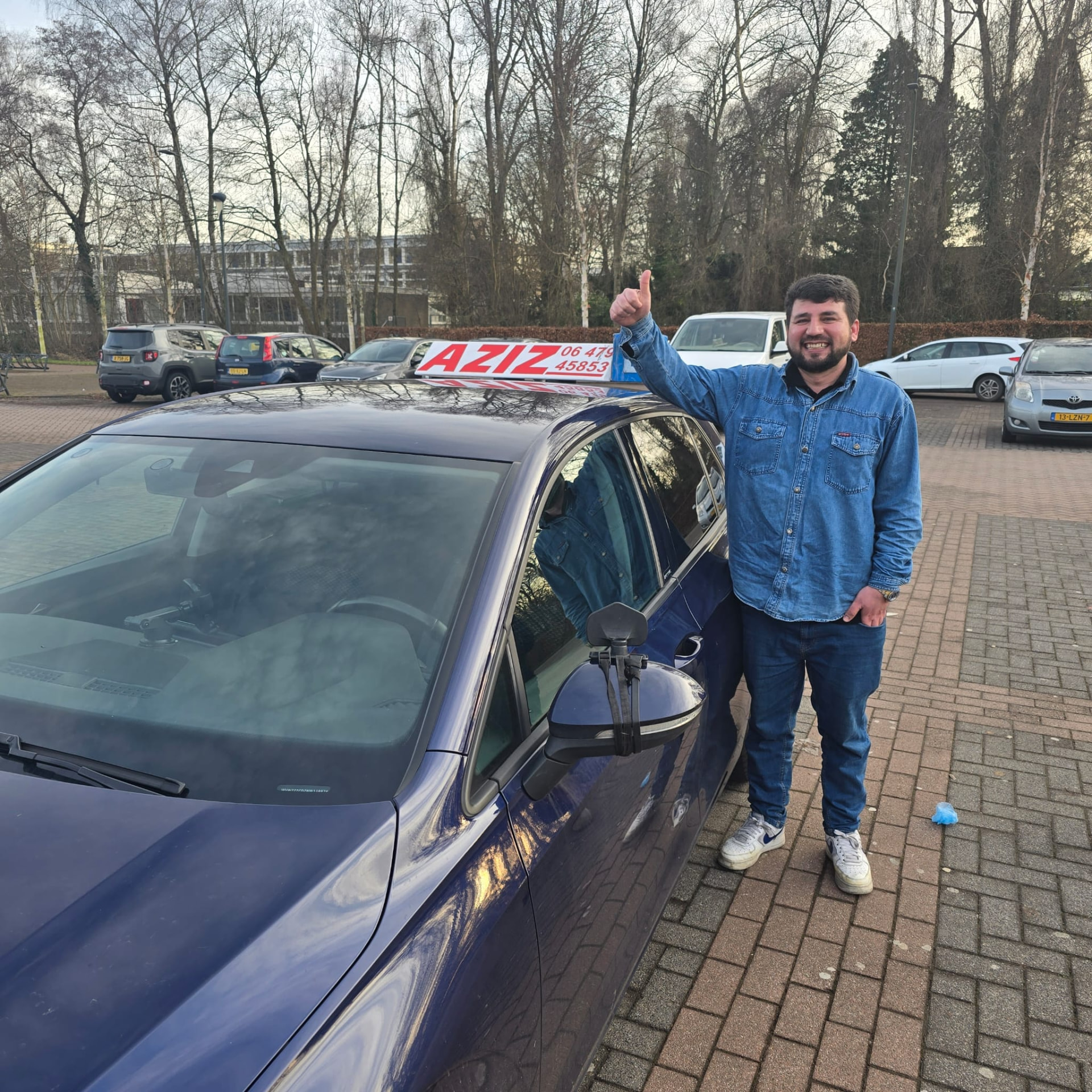 Geslaagde leerling naast de lesauto